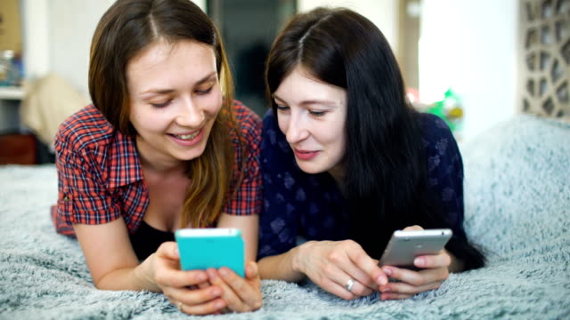 Zwei-glückliche-Frauen-Freunde-teilen-von-sozialen-Medien-in-ein-smart-Phone-und-reden