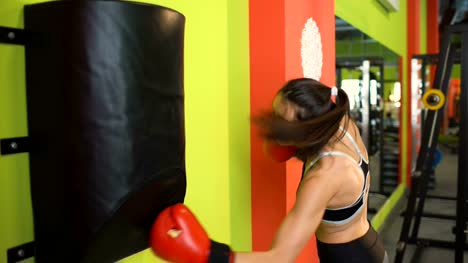Young-woman-boxer-hit-punching-bag-during-pre-match-warm-up-in-boxing-club
