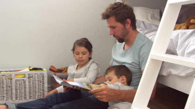 Vater-liest-Geschichte-zu-Kindern-in-ihrem-Schlafzimmer