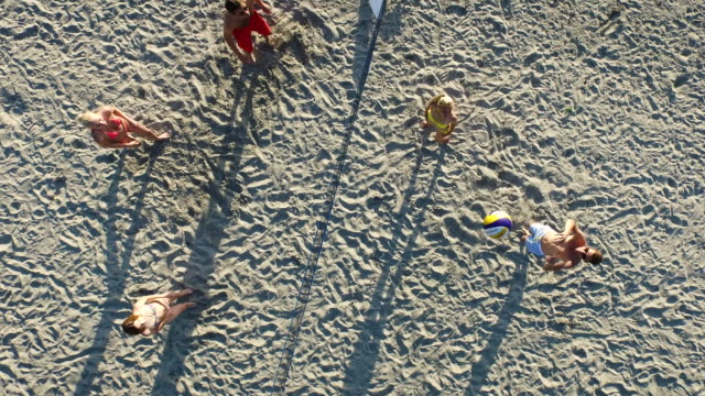 Aerial-drone-shot-of-people-playing-beach-volleyball-near-the-sea.