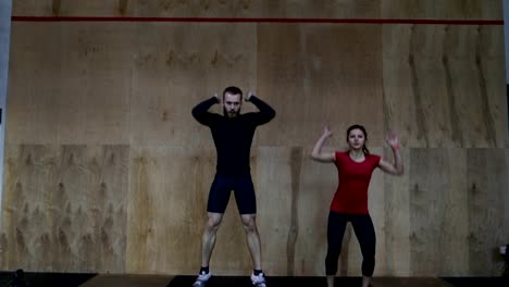 Pareja-de-jóvenes-atletas-haciendo-ejercicio-de-Burpee-durante-el-entrenamiento-de-ejercicio-en-el-gimnasio