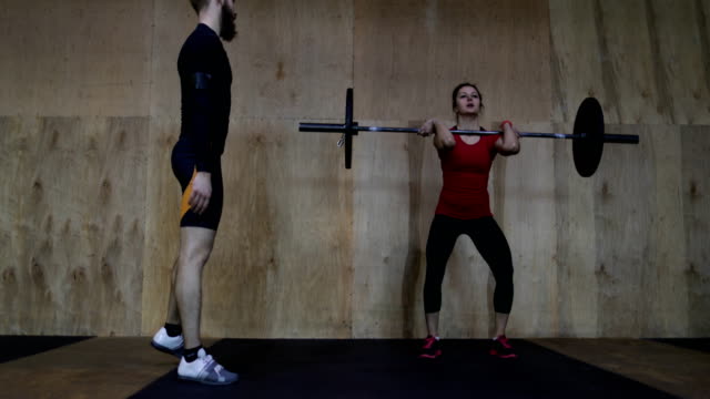 Mujer-atlética,-levantamiento-de-pesas-trabajando-con-Entrenador-Personal-en-gimnasio