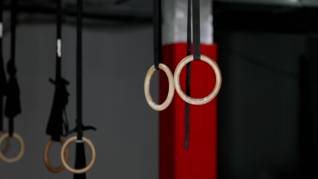Young-Man-Exercising-On-Gymnastic-Rings-During-Workout-Training-At-Gym