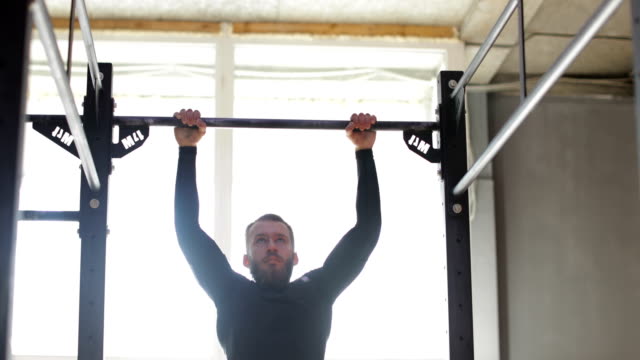 Mann-hängen,-Bar,-Kerl-dabei-hochziehen-Übung-beim-Workout-Training-im-Fitnessstudio
