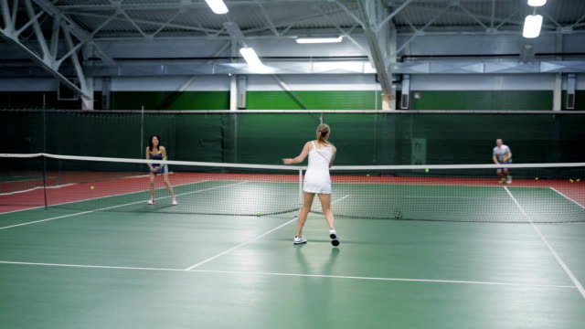 Two-teams-playing-tennis-in-double-game.-Women-and-men-players-practicing