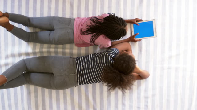 Vista-aérea-de-adolescentes-mirando-Tablet-Digital-en-cama