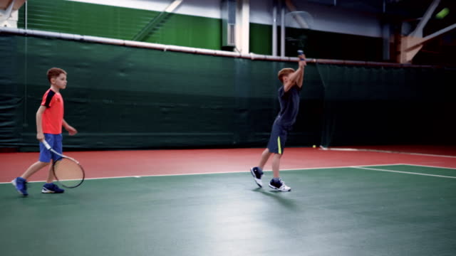 Dos-muchachos-jóvenes-con-raquetas-de-tenis-en-cancha-juntos