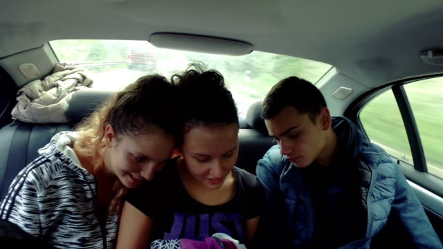 Tres-adolescentes-miran-red-social-smartphone-de-conducción-en-la-parte-trasera-de-coche-de-lujo