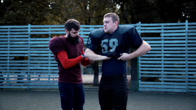 Man-helping-his-mate-to-put-on-football-jersey