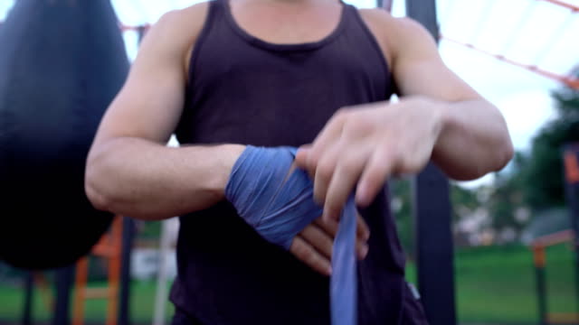 Starke-Kickboxen-Mann-Stanzen-Wraps-aufsetzen-und-Faust-seine-Hand-hinein.