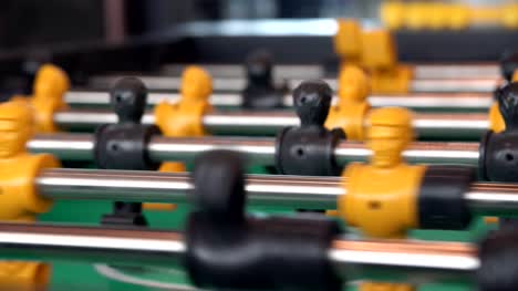 close-up-yellow-players,-young-man-playing-enjoy-foosball-wooden-table-soccer-game