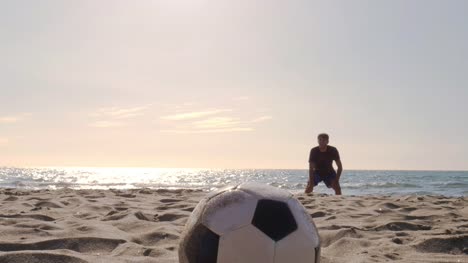Junger-Mann-Torhüter-in-der-Badehose-spart-Fußball-Strafe-am-Ufer-Meeres-am-Strand-bei-Sonnenuntergang-silhouette