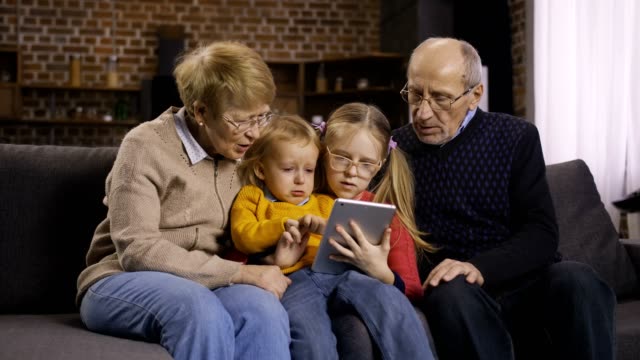 Familie-mit-tablet-pc-auf-Sofa-zusammen-zu-Hause