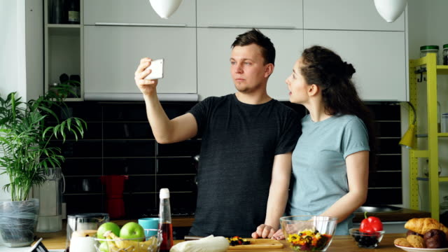 POV-junge-Brautpaar-mit-online-video-Anruf-mit-Smartphone-Kamera-beim-Kochen-in-der-Küche-zu-Hause