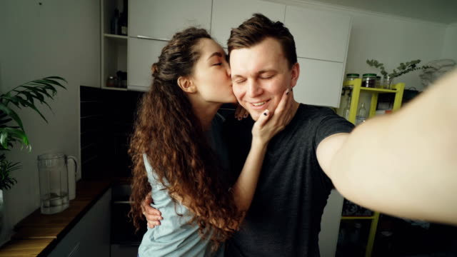 POV-junge-Brautpaar-mit-online-video-Anruf-mit-Smartphone-Kamera-stehend-in-der-Küche-zu-Hause