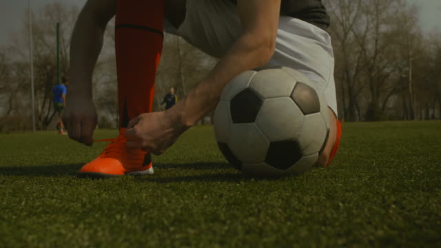 Soccer-player-tying-shoelace-on-football-pitch