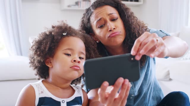 Junge-schwarze-Frau-und-Tochter-nehmen-Selfie-Grimasse