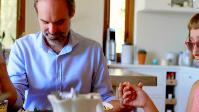 Family-praying-together-before-having-breakfast-in-kitchen-4k