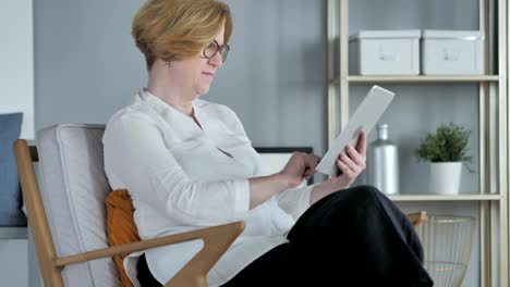 Senior-mujer-navegar-por-Internet-en-Tablet-PC,-sentado-en-el-sofá