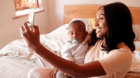 Mother-with-baby-son-video-chatting-on-smartphone-at-home