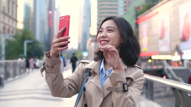 Slow-Motion-ziemlich-glücklich-junge-asiatische-Frau,-die-zu-Fuß-in-der-Stadtstraße-mit-Smartphone-am-Nachmittag