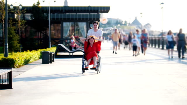 Guy-rollt-ein-fröhliches-Behinderte-Mädchen-im-Rollstuhl-am-Wasser