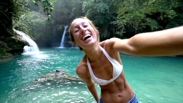 Joven-tomando-selfie-retrato-con-una-hermosa-cascada-en-la-isla-de-Cebú-en-Filipinas.-Personas-viajan-selfie-concepto-de-naturaleza.-Una-persona-sólo-disfrutando-al-aire-libre-y-la-tranquilidad-en-un-entorno-tranquilo-Slow-motion-video