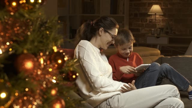 Niño-y-su-madre-utilizando-una-tableta-digital-juntos-en-Navidad