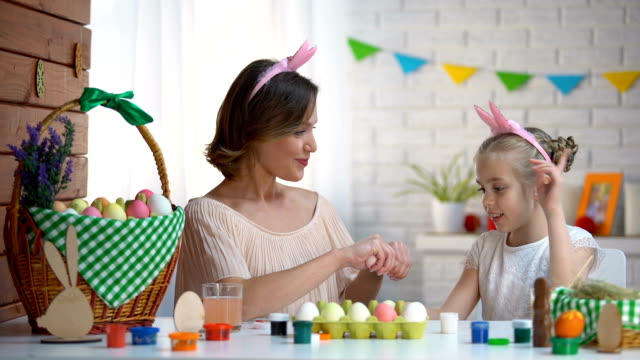 Fröhliche-Mutter-und-Tochter,-die-Vorbereitung-auf-Ostern-mit-dekorierten-Eiern-spielen