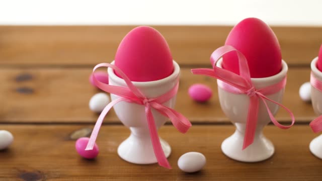 pink-easter-eggs-in-holders-and-candies-on-table