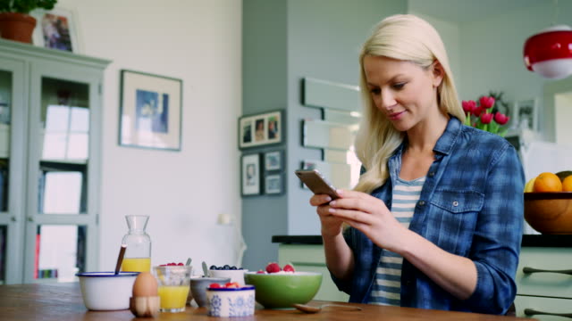 Beautiful-Blond-Woman-Using-Smart-Phone-To-Photograph-Breakfast