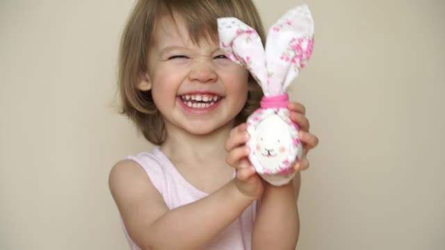 Portrait-of-little-cute-child-girl-laughs-and-smiles-holding-in-hand-chicken-egg-decorated-for-Easter-bunny.