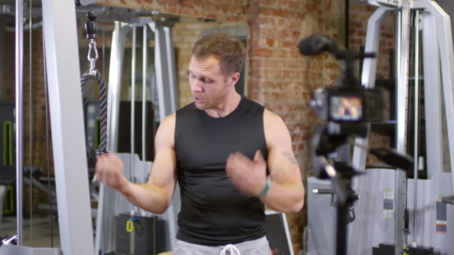 Muskulöser-Blogger-zeigen-Übung-mit-Pulley-Machine-auf-Kamera