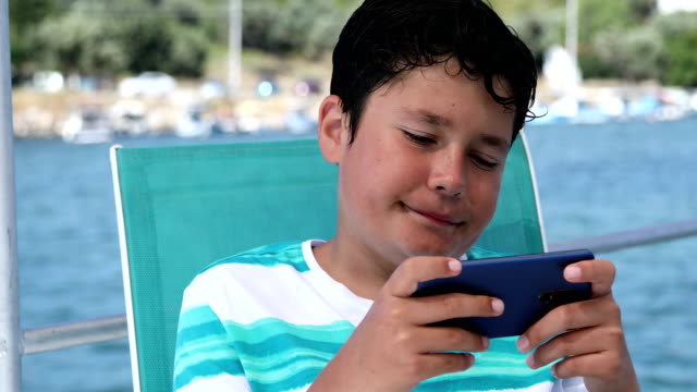 Junge-auf-dem-Boot-mit-dem-Smartphone