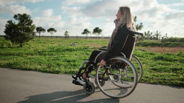 Young-woman-is-sitting-in-invalid-carriage-and-moving-in-park-area