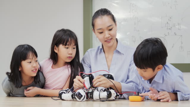 Gruppe-von-Schülern-und-Lehrern-in-der-Roboterklasse.-Berater-in-der-Studentin-über-ihr-Roboterprojekt-erklären.