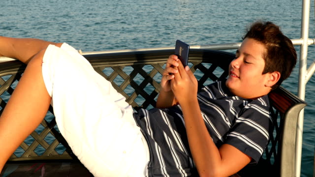 Kind-auf-Yachtdeck-mit-Smartphone