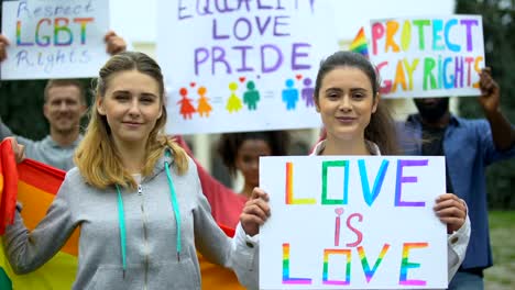 Positive-Menge-hebt-Regenbogensymbole-und-Plakate-für-LGBT-Rechte,-Stolz-Marsch