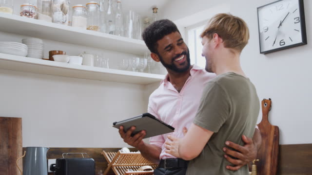Männliche-Homosexuell-Paar-mit-digitalen-Tablet-zu-Hause-in-der-Küche-zusammen