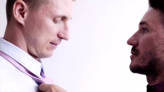 Gay-man-help-his-partner-putting-on-tie-for-job-interview.-Push-necktie.