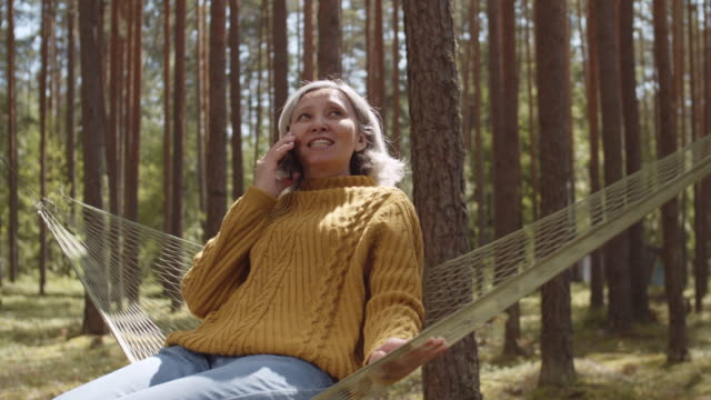 Woman-Sitting-in-Hammock-and-Talking-on-Telephone