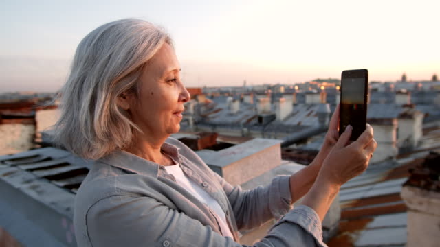 Grey-haired-Female-Tourist-Shooting-Video-on-Roof