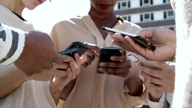 Low-Winkel-Ansicht-von-jungen-Menschen-mit-Smartphones