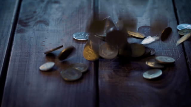 Haufen-von-Münzen-fallen-auf-dem-Holztisch