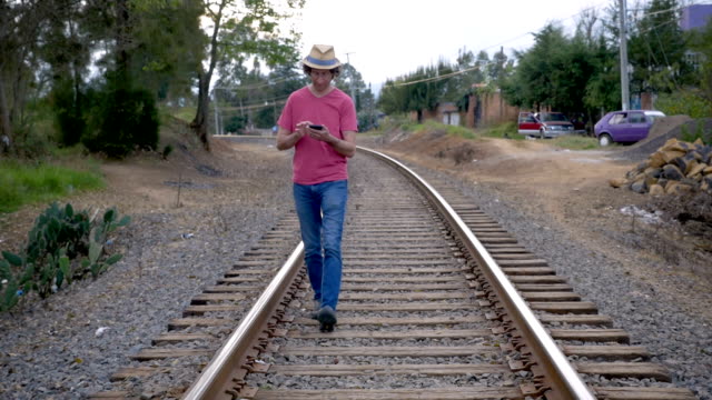 Mann-zu-Fuß-auf-Eisenbahnschienen-mit-seinem-Smartphone