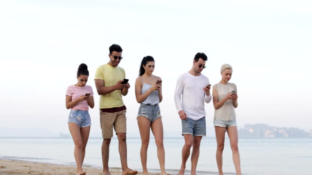 Menschen-zu-Fuß-am-Strand-mit-Smart-Phones,-junge-Touristen-Zellgruppe-Networking-Online