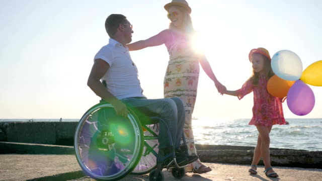 behinderte-Menschen-im-Rollstuhl-mit-Tochter-und-Frau-auf-Hintergrund-blauer-Himmel