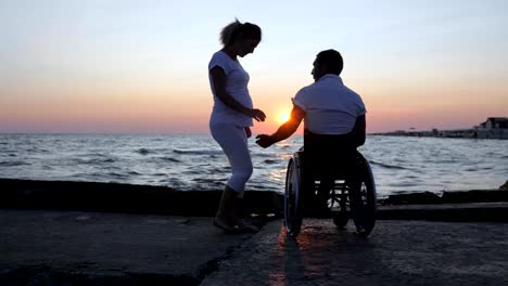 Disabled-and-woman-lift-up-hands-in-evening,-handicapped-with-pregnant-girl-watching-sunset,-expecting-baby,-husband