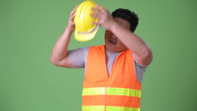Trabajador-de-la-construcción-del-joven-guapo-asiáticos-con-sobrepeso-sobre-fondo-verde