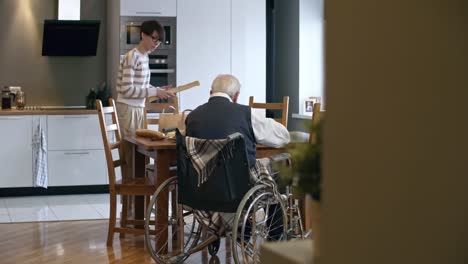 Young-Woman-Unpacking-Groceries-for-Senior-Man